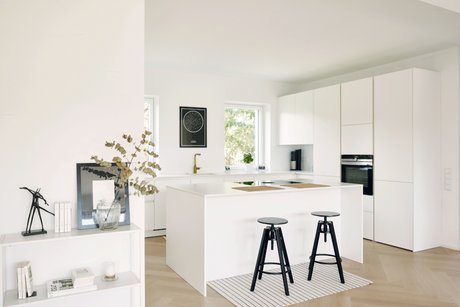 Weiße Inselküche mit Bar und schwarzen Dreh-Barhockern