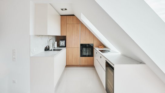 Weiße Küche bestehend aus zwei Küchenzeilen mit holzfarbenem Hochschrank