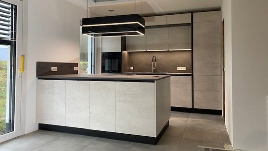 Kompakte kleine Inselküche in hellgrauer Betonoptik mit dunkler Arbeitsplatte
