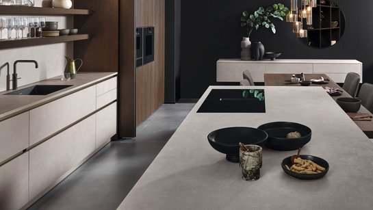 Inselküche in Betonoptik kombiniert mit dunklem Holzfurnier