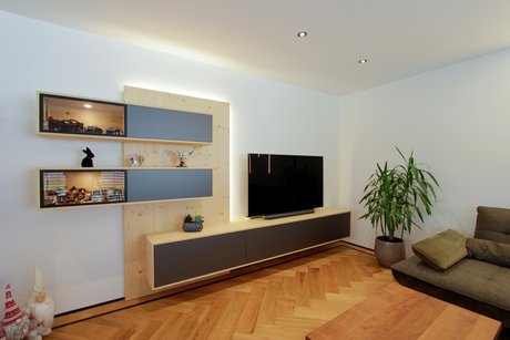 Zwei hängende längliche Wandregale, halb mit grauer Front, halb Vitrine, darunter ein Sideboard mit grauer Front